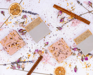 Various soap bars with natural elements like lavender, cinnamon, and orange on a light background
