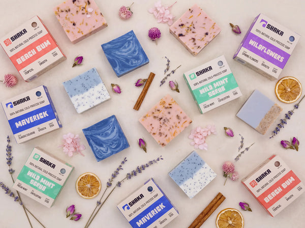 Various natural soap bars and packaging on a light background with flowers and herbs.
